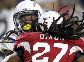 Arizona Cardinals defensive back Travell Dixon hits Los Angeles Chargers wide receiver Geremy Davis in a 2018 preseason game. Dixon was charged with a penalty under the new helmet rule. (Image: Ross D. Franklin/AP)