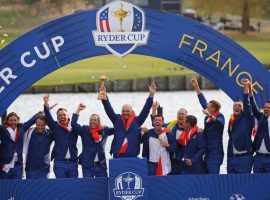 European captain Thomas Bjorn holds the trophy as his team celebrates after winning the 2018 Ryder Cup. (Image: Francois Mori/AP)