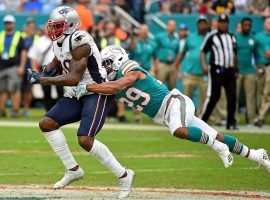 Josh Gordon (left), wide receiver from the New England Patriots, attempts to evade a tackler against the Miami Dolphins. (Image: Jasen Vinlove/USA Today Sports)