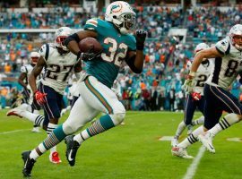 Running back Kenyan Drake from the Miami Dolphins sprinting to the end zone to evade Rob Gronkowski from the New England Patriots. (Image: Michael Reaves/Getty)