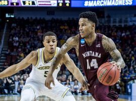 Ahmaad Rorie from the Montana Grizzlies drives by a Michigan defender during a game in the 2018 March Madness tournament. (Image: Todd Goodrich/Montana Athletics)