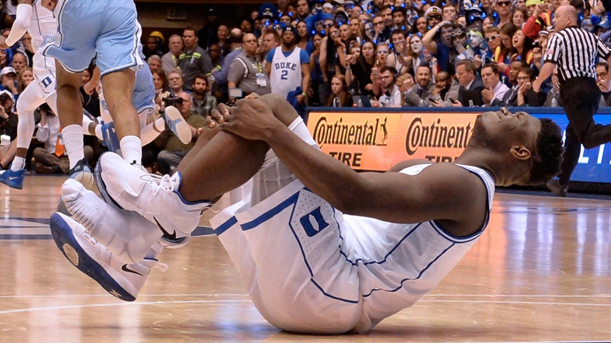 Zion Williamson of the Duke Blue Devils winces in pain after his sneaker burst open and he slipped in a Duke/North Carolina game in Durham, NC. (Image: Chuck Liddy/Charlotte News Observer)