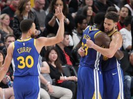 Steph Curry (left) of the Golden State Warriors looks on as teammates Draymond Green and Klay Thompson embrace after locking up a victory against the Portland Trailblazers in Portland. (Image: Porter Lambert/Getty)