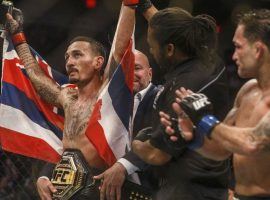 Max Holloway (left) celebrates his unanimous decision victory over Frankie Edgar (right) after the main event of UFC 240. (Image: Jason Franson/CP)