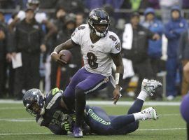 Baltimore Ravens QB Lamar Jackson evades a tackler against the Seattle Seahawks in Seattle WA. (Image: Elaine Thompson/AP)