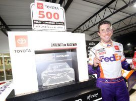 Denny Hamlin â€“ wearing a mask depicting his own smile â€“ celebrates after winning the Toyota 500 at Darlington Raceway on May 20, 2020. (Image: Chris Graythen/Getty)