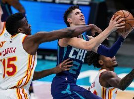 Atlanta Hawks center Clint Capela tries to block Charlotte Hornets guard LaMelo Ball, who would make NBA history as the youngest pro to notch a triple-double. (Image: Suzanne Greenberg)