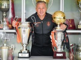 Dan Petrescu poses in CFR's trophy room after winning a third consecutive Romanian title in 2020. (Image: cfr1907.ro)