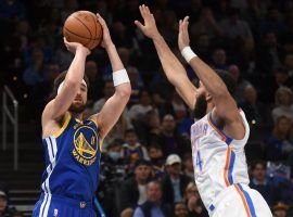 Klay Thompson from the Golden State Warriors shoots a 3-pointer while Darius Bazley from the Oklahoma City Thunder attempts to defend him. (Image: Kyle Philips/AP)