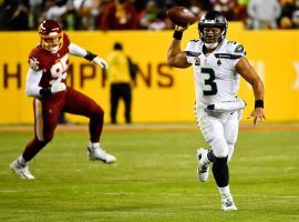 Russell Wilson from the Seattle Seahawks scrambles while defenders from the Washington Commanders pursue him. (Image: Thomas York/Getty)